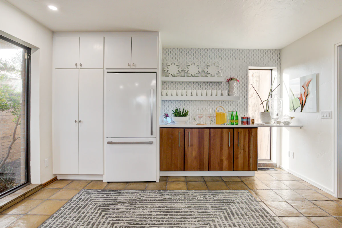 Bright kitchen with a built-in white refrigerator freezer beside tall white cabinets and a wooden counter with shelves